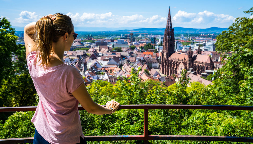 Eine Frau schaut in Freiburg im Breisgau auf das Freiburger Münster und die Innenstadt