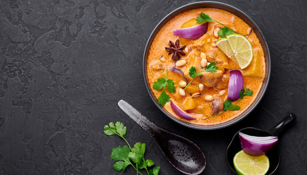 Massaman Curry in einer schwarzen Schüssel auf dunklem Schieferhintergrund