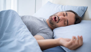 Ein schnarchender Mann liegt im Bett.